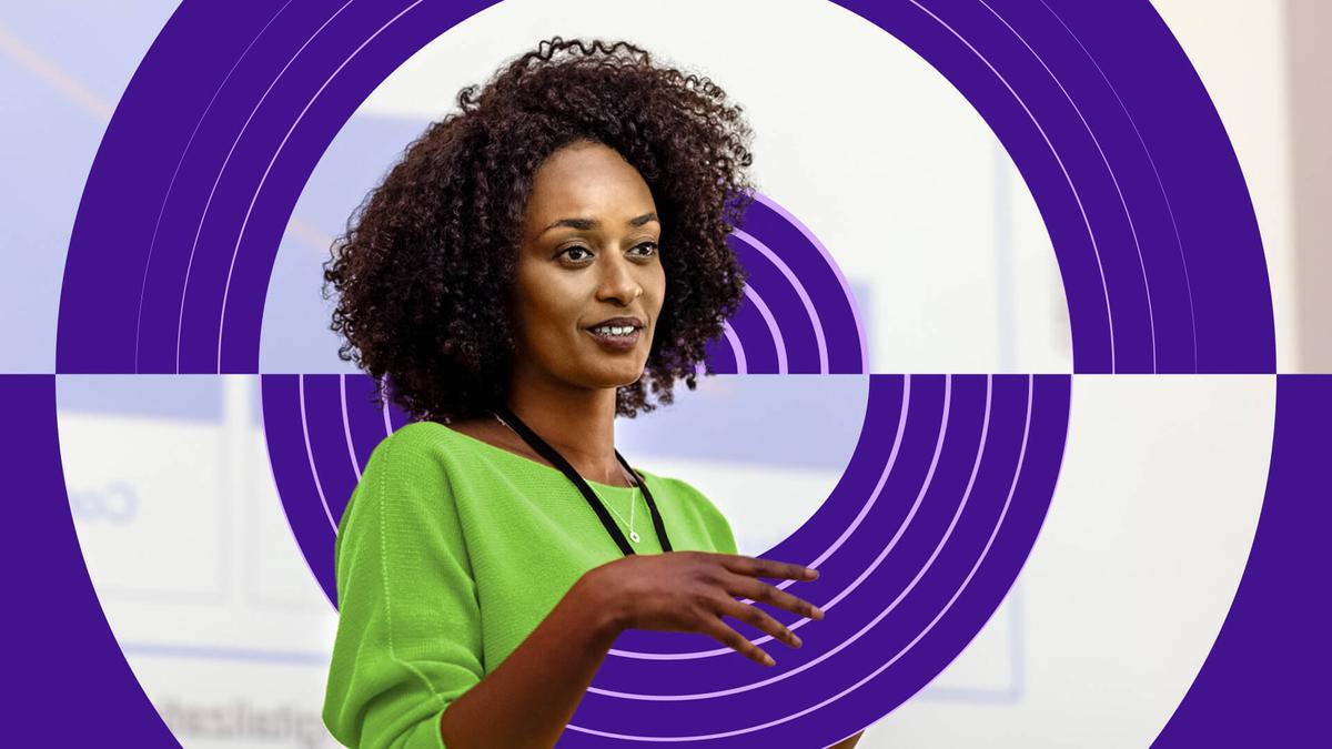 A woman is presenting in front of a purple circle.